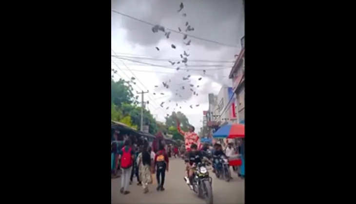 A young man throwing money on a busy road in Hyderabad.